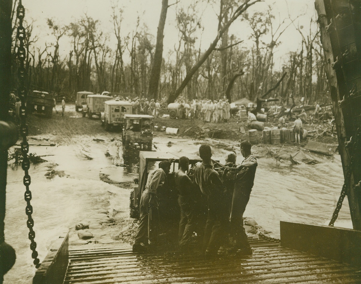 Load Cape Gloucester Wounded, 1/19/1944. New Britain - - U.S. Coast Guardsmen, who’ve just finished the bow doors of this Coast Guard manned LST (Landing Ship, Tanks) beached at Cape Gloucester, New Britain, now loan wounded onto the ship from ambulances backed up to the loading ramp.  The LST’s officers’ wardroom was converted into an emergency hospital.Credit (U.S. Coast Guard photo);