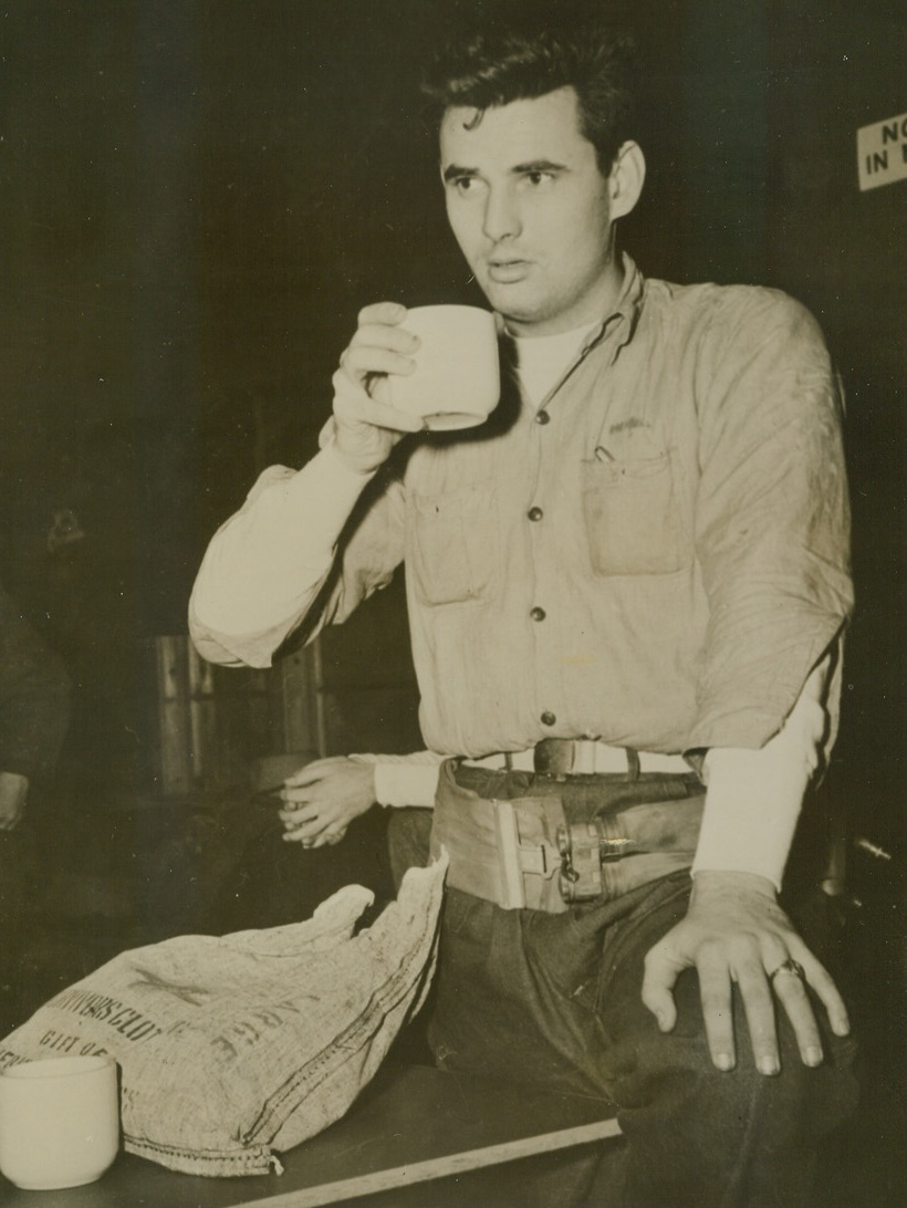 Survivor of Explosion, 1/3/1944. Sandy Hook, N.J. - Brought to the Sandy Hook Coast Guard Station after he survived the explosion and sinking of a U.S. Destroyer at the entrance to New York Harbor on January 3rd, Radioman I/c David L. Merrill, 21, of Henrietta, Texas, sips hot coffee. Beside him is the Red Cross “Survivor” kit of warm clothing, given him at the station. Credit: Official U.S. Navy photo from ACME;