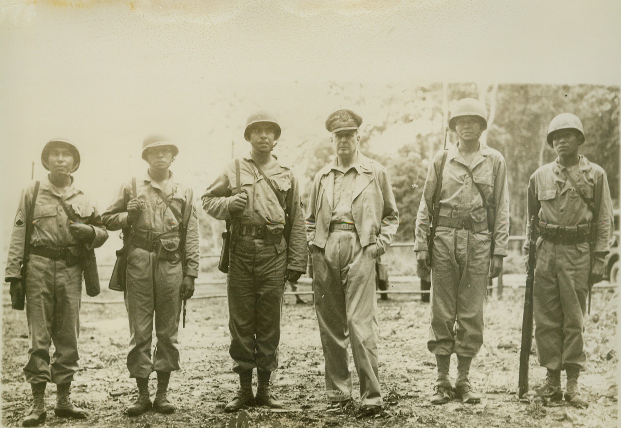 Five Indian Tribesmen Meet a Chief, 1/19/1944. Somewhere in the Southwest Pacific—Gen. Douglas Macarthur, Commander-in-Chief of Allied Forces in the Southwest Pacific, meets representatives of five different American Indian tribes in one U.S. Army unit. S/Sgt. Virgil Brown (Pima), Phoenix, Ariz.; Sgt. Virgil F. Howell (Pawnee), Pawnee, Okla.; S/Sgt Alvin J. Viloan (Chitmatcha), Charenton, LA.; General Macarthur; Sgt. Byron L. Tsignine (Navajo), Ft. Defiance, Ariz.; Sgt. Larry L. Dekin (Navajo), Copper Mine Ariz. (U.S. Signal Corps Photo).;