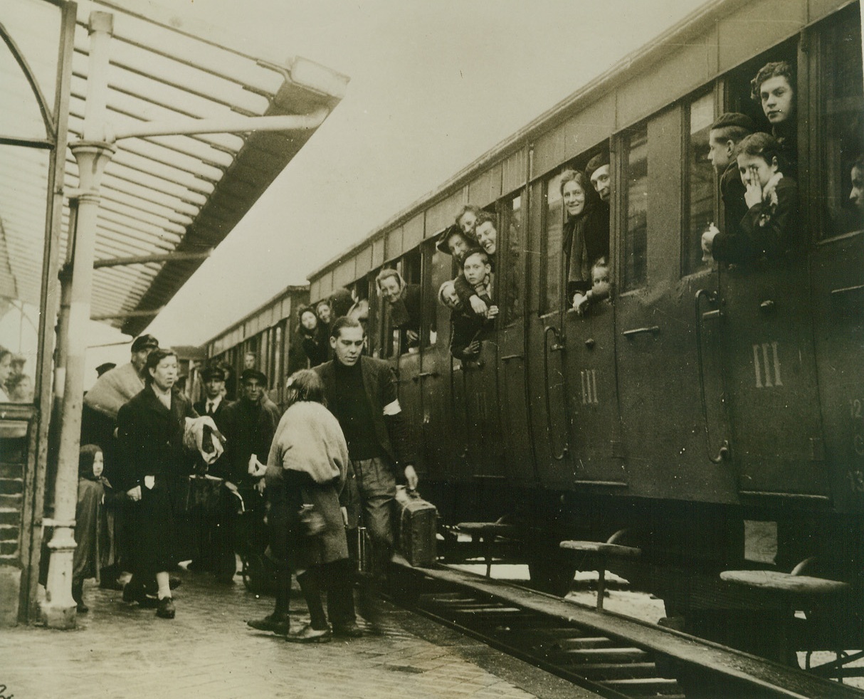 Siege Brings Luxury, 10/9/1944. DUNKIRK, FRANCE – Smiling civilians of Dunkirk crowd the windows of an evacuation train as they wait to leave the city during the 60 hour truce.  The need for hurrying non-combatants out of the battle area put the wartime luxury of train travel within their grasp.Credit:-- WP—ACME 10/9/44;