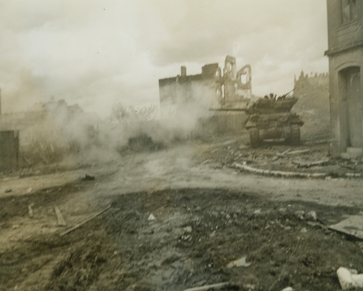 ACTION IN AACHEN, 10/19/1944. GERMANY--Gun blazing away at enemy positions off to the left, an American tank rolls through a battered street in Aachen.Credit: Photo by Acme photographer, Andrew Lopez, for the War Picture Pool;