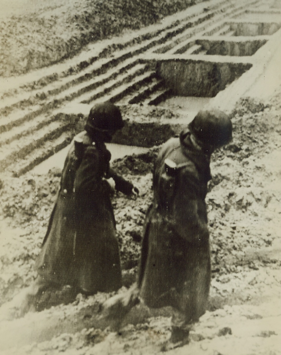 Tough Going in Germany, 10/13/1944. GERMANY – Wearing boots and their winter overcoats, these Yanks trudge slowly through the deep mud past a captured Nazi tank trap, which is a series of cleverly constructed steps, ending in a hollow with a wall in front. Heavy rains continue to bog down operations on the German frontier. Credit (Signal Corps Radiotelephoto from ACME);