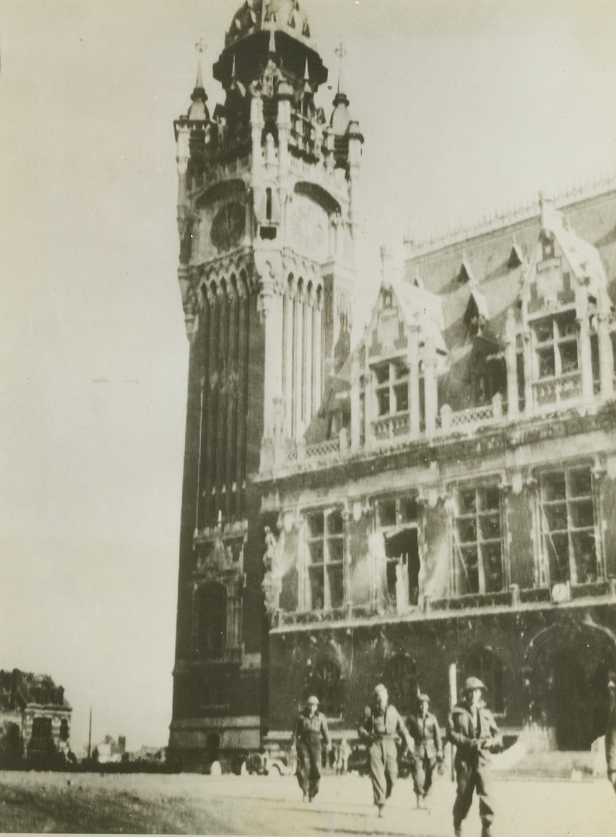 CANADIANS PASS CALAIS LANDMARK, 10/4/1944. A group of Canadian troops on patrol in the French port of Calais, pass the famous clock tower which, on a clear day, can be seen from Dover, England, across the Channel. Credit Line (ACME Photo via Army Radiotelephoto);