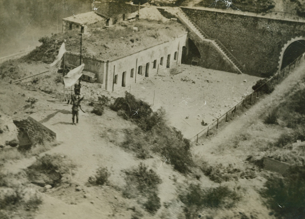 German Garrison Surrenders to US Plane, 10/1/1944. France – Waving high the white flag of surrender, a German soldier walks out from a Nazi-held fort on the coast of France, which was under fire from the guns of the USS Quincy. This photo was taken from a US plane, which radioed back to the warship that it could cease firing. The plane had been flying over the fort to direct the fire from the ship. Credit: Official U.S. Navy photo from ACME;