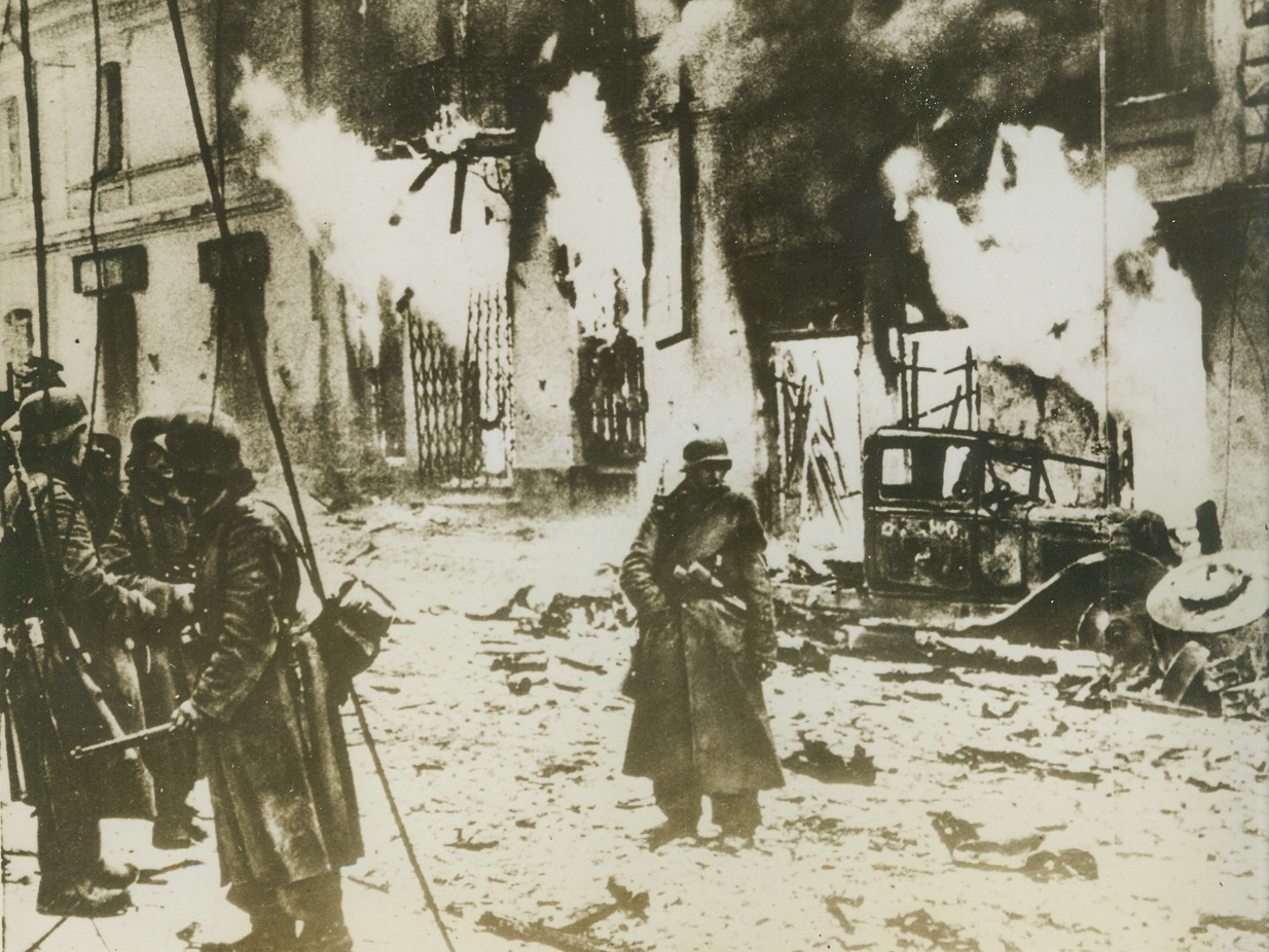 Embattled Zhitomer, 2/11/1944. Zhitomer, U.S.S.R. – Four times a battlefield, the important industrial town of Zhitomer in the Kiev sector of the Ukraine lay in ruins when the Red Army finally drove the Nazis from the stronghold. Here a German demolition squad stands by to watch its handiwork near completion as a row of buildings burn to the ground. Photo obtained through a neutral source. Credit: (ACME);