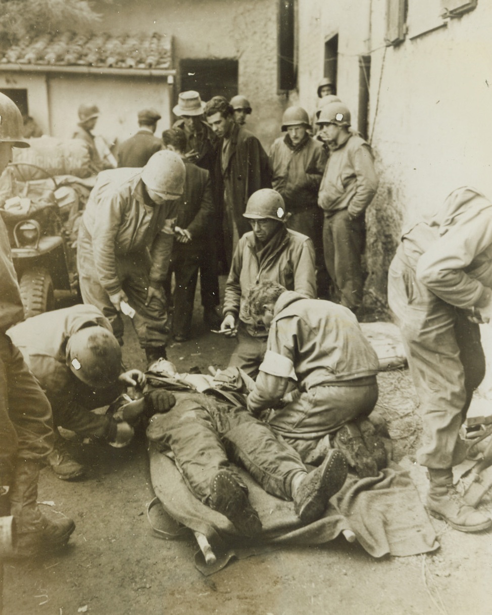 Worried Peasants, 2/11/1944. ACCRIELLA, ITALY -- Looking very much concerned, natives of Accriella stand by as first aid is given to a wounded Fifth Army warrior. The Yank had been injured in nearby patrol action just a few minutes before, as the Allies drove inland after their landing at Nettuno. Credit Line - WP- (ACME) Photo by Bert Brandt for the War Picture Pool;