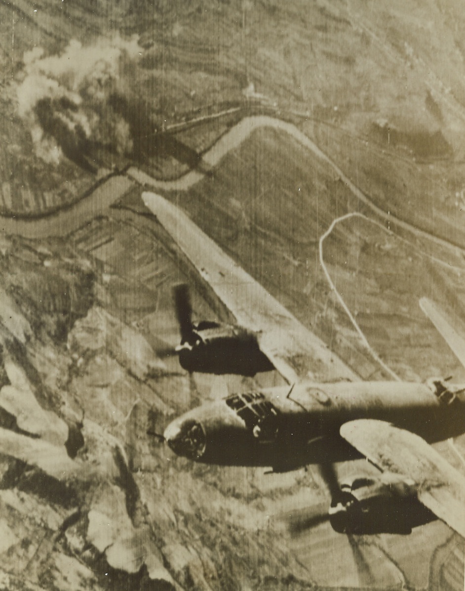 Nazi Communications Walloped From Air, 2/14/1944. ORTE, ITALY -- A B-26 Marauder wings over enemy marshalling yards at Orte, Italy, as smoke (background) marks an Allied bomb-hit on the enemy supply link to Nazis battling at Anzio. The return of fair flying weather has brought out Allied warplanes in a round-the-clock assault against the Germans in Italy. Credit (Signal Corps Radiotelephoto from ACME);