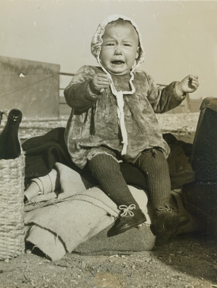 “Hell Hath no Fury Like a Woman Scorned”,  2/11/1944. ITALY – Loudly bewailing temporary desertion by her mother, this little Italian miss is too young to seek consolation from that interesting looking basket at the left. She and her mother had a one-way ticket to the American lines of the Cassino front. The Yanks help them to Allied territory, but they are forbidden a return visit to Nazi-land. That is, if anyone wants to return. Credit (ACME Photo by Charles Seawood, War Pool Correspondent);