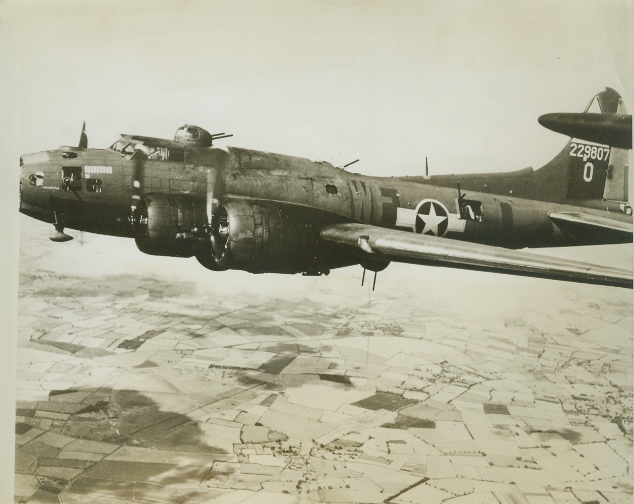 Fortress' Last Flight, 2/17/1944. This photo of the gallant Flying Fortress, "Lady Liberty", veteran of nine bombing missions (note score just below and in front of pilot's compartment), was taken only a few seconds before flak from a German anti-aircraft battery blasted the ship in half, over Flushing, Holland. Here, the ship's pilot, Lt. Ralph R. Miller, of Chicago, can be seen through the window of the control cabin while, aft, a waist gunner can be seen at his post. Credit: (U.S. Army Air Force Photo from ACME);