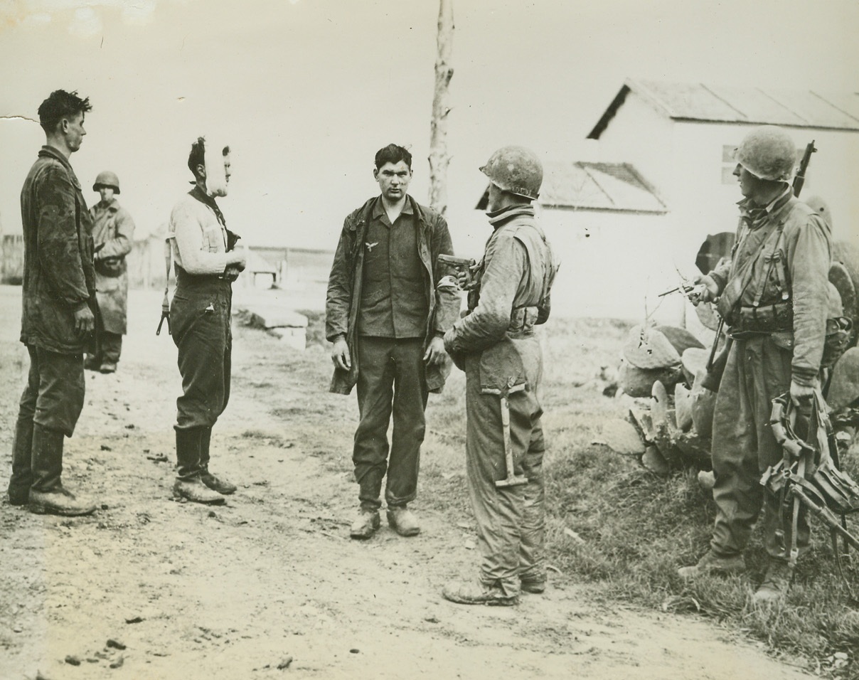 THEIR SNIPING DAYS ARE DONE, 2/24/1944. ACCIARELLA, ITALY—Three hatless German snipers (left), who were rounded up by members of an American paratrooper unit, which had suffered casualties from snipers in the Acciarella area. The Paratroopers at right, carries bayonets and cartridge belts taken from the Germans. The third sniper from left, wears a Red Cross arm band, but when captured carried a gun which had been fired. Another sniper shows a bandaged jaw.  Credit Line (U.S. Signal Corps Photo from ACME);