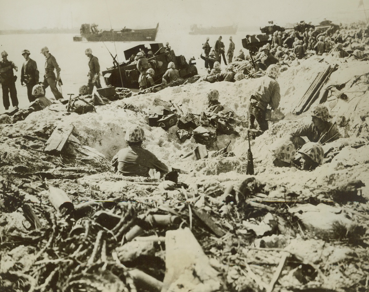 From Shellhole to Foxhole, 2/14/1944. Marshall Islands – U.S. Marines take advantage of the protection offered by shell holes as tanks, half-tracks and other equipment are unloaded from their landing craft on Namur Island where the heaviest fighting of the recent Marshalls action took place.  The Leathernecks eliminated all enemy resistance on the island within 24 hours.Credit (U.S. Marine Corps photo from ACME);