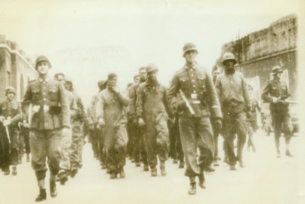 Allied Prisoners, 2/25/1944. Rome -- Two pompous Nazis lead five columns of British and American soldiers, captured in the fighting at Nettuno, through the streets of Rome, according to the German caption accompanying this photo. Note the Coliseum in background. Obtained through a neutral source.  2/25/44 (ACME);