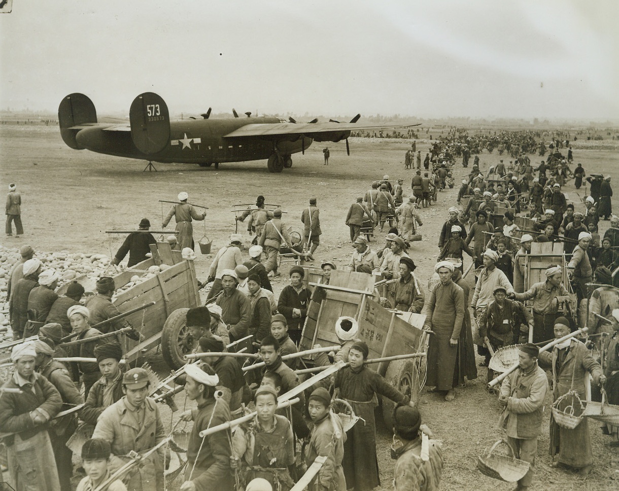 Airfield-Handmade, 3/31/1944. China – Lack of modern equipment and machinery isn’t stopping the resourceful Chinese from building modern airfields in China. Three hundred thousand Chinese workers have been conscripted to do the job. A hundred thousand little handmade wheelbarrows are used to transport materials – and even the chipping of stones for the runways is done by hand. American Engineers, working in conjunction with Chinese Army Engineers, are supervising the job. Photo shows: Long lines of laborers use every conceivable means of conveyance in transporting stones and dirt to build the runway. Credit: ACME photo by Frank Cancellare for the War Picture Pool;