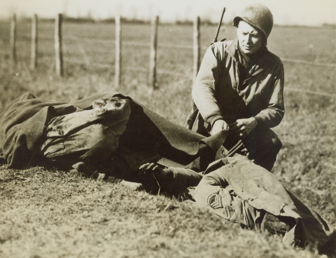 SORROWFUL FAREWELL, 4/21/1944. ON THE FIFTH ARMY BEACHHEAD—A mixture of sorrow and anger appears on Pfc. Earl H. Brandell’s face as the covers the bodies of two of his fighting friends who were killed by Nazi machine gun fire. The soldiers were killed during attack by Allied 5th Army infantrymen on enemy positions in the Anzio beachhead area in Italy. Brandell is from Fort Atkinson, Wis.Credit: US Army photo from Acme;