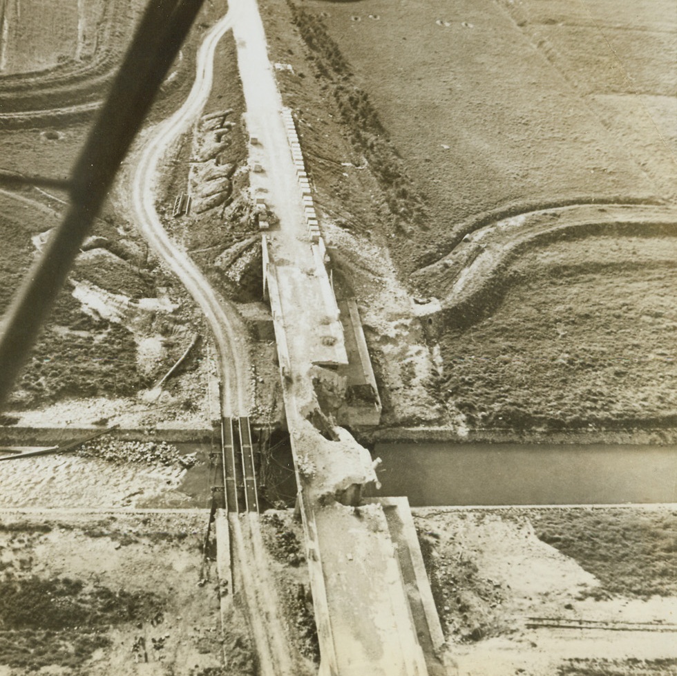 Detour on Anzio Beachhead, 4/22/1944. ANZIO, ITALY – Blown up into uselessness by the retreating enemy, the permanent bridge over the Mussolini Canal has been replaced by a temporary one built by the Allies to carry supplies to their forward lines. The Germans are entrenched in an area five hundred yards from the Canal.Credit (Acme) (WP);