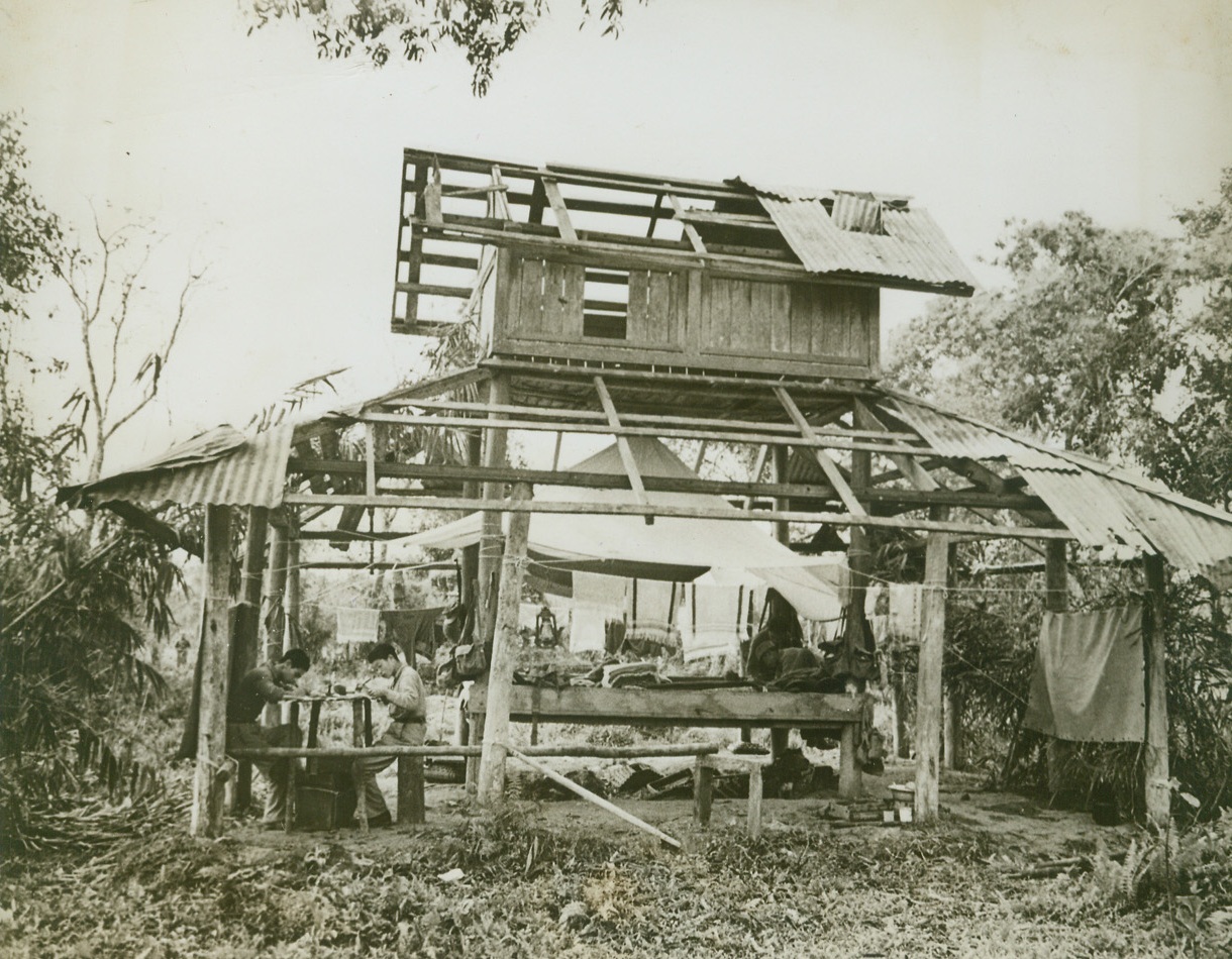 ALL THE COMFORTS—, 4/7/1944. MAINGKWAN, BURMA—Chinese officers, members of the valiant Allied force fighting under General Stilwell in Burma, set up housekeeping in the ruins of a temple at Maingkwan. Two men work at an impromptu desk at left, while a third fixes the “bed” in center. Bedclothes and wash hang from lines strung between the supports of the shattered building. Credit: Acme;