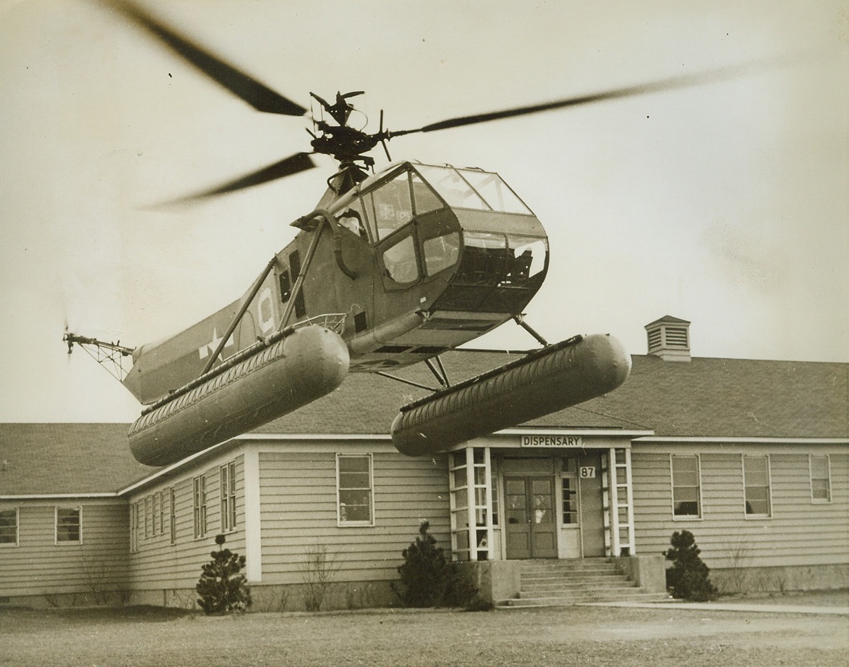 Helicopter to the Rescue, 4/18/1944. NEW YORK CITY -- The Third Naval District's air arm of the U.S. Coast Guard is now using helicopters for patrol and rescue assignments. While such uses are admittedly in experimental stages, Coast Guardsmen have found that, particularly in the case of rescue work, the little plane is speedier and eliminates much of the rough handling unavoidable in other methods of rescue. In a recent demonstration (above) the helicopter delivers a "wounded" flier picked up from the sea to the very door of the dispensary. The plane descends slowly, vertically so that there is very little jarring. Credit: (Coast Guard Photo from ACME);