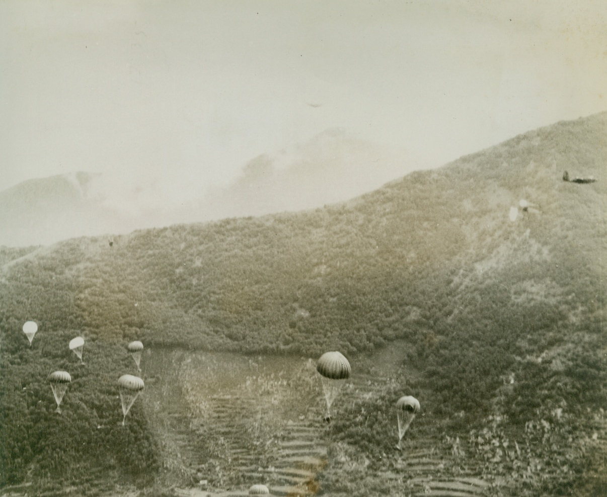 ‘Chuting Supplies in Italy, 5/31/1944. ITALY – Allied troops fighting forward in the current push toward Rome, moved ahead in some parts of the Italian mountains so fast that mule trains with supplies and ammunition couldn’t keep pace with them.  Here in a misty gorge, small parachutes are carrying down supplies brought to the fighting men by a-20’s of the USAAFCredit:  USAAF PHOTO from ACME;