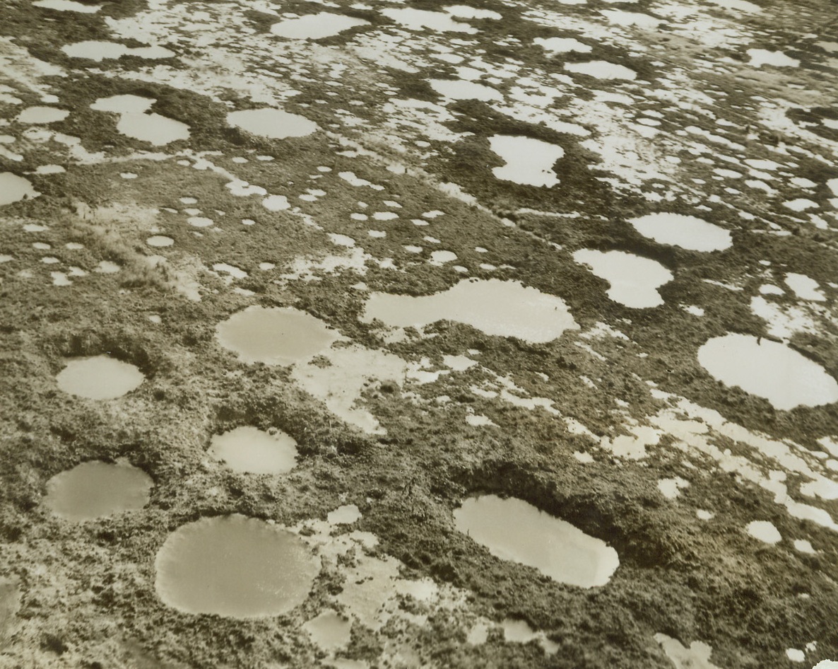 Raid Perimeter, 5/24/1944. CASSINO, ITALY—Closely-spaced bomb and shell craters dot the edges of Cassino. Many of them are markers of the great bombing raid that was designed to “fumigate” the town. Since these craters are really outside the town, they mark target misses. Credit: ACME Photo by Charles Seawood, War Pool Correspondent.;