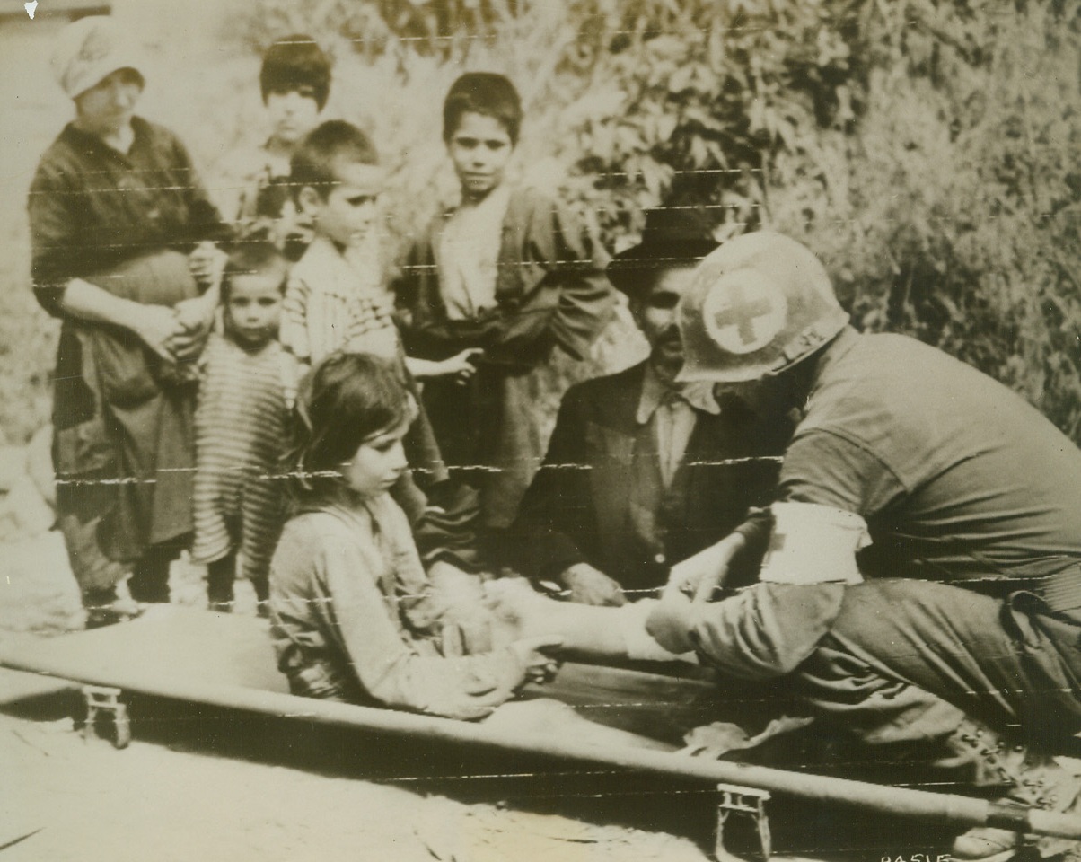 With the Greatest of Care, 5/18/1944. ITALY – A member of the U.S. Army Medical Corps tenderly and gently dresses the leg of a young Italian girl who was wounded in the Castelonorato area during the latest drive. This photo was flashed by Army Radiotelephoto.Credit (U.S. Army Radio from ACME);