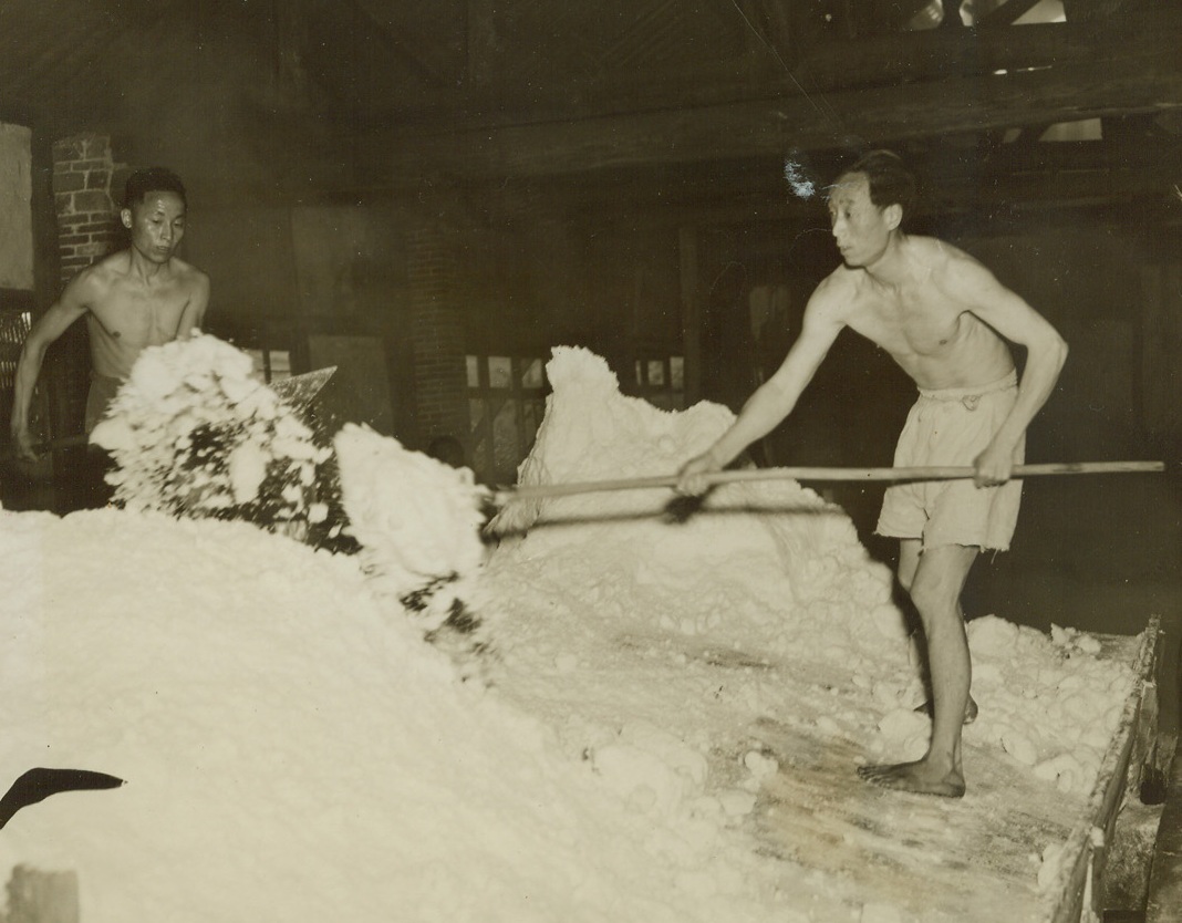 Salt for the Cellars of China, 5/23/1944. Tse Liu Ching, China – One of the most thriving industries in this area of China is the salt mines located at Tse Liu Ching. These mines, 2,600 years old, are cultivated by rustic methods, but nevertheless produce 250,000 metric tons of salt a year, or one fourth of all the salt produced in free China. Three hundred thousand laborers work the mines, from which salt is shipped to all parts of the East. Picture shows: The salt brine is boiled to remove all the moisture. Credit: ACME photo by Frank Cancellare, War Pool Correspondent;