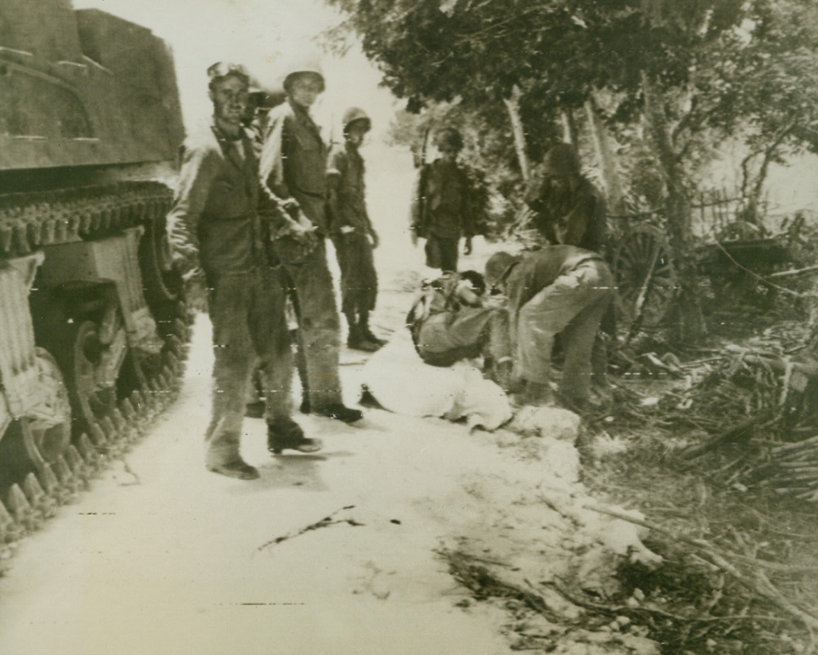 YANK CASUALTY ON SAIPAN, 6/24/1944. SAIPAN—An American casualty, wounded in an attempt to storm a Jap pillbox, is cared for by medical corpsmen on Saipan. American patrols have succeeded in penetrating to the capital city of the Japanese Marianas meeting almost no opposition along the way.  Credit (Signal Corps Radiotelephoto from ACME);