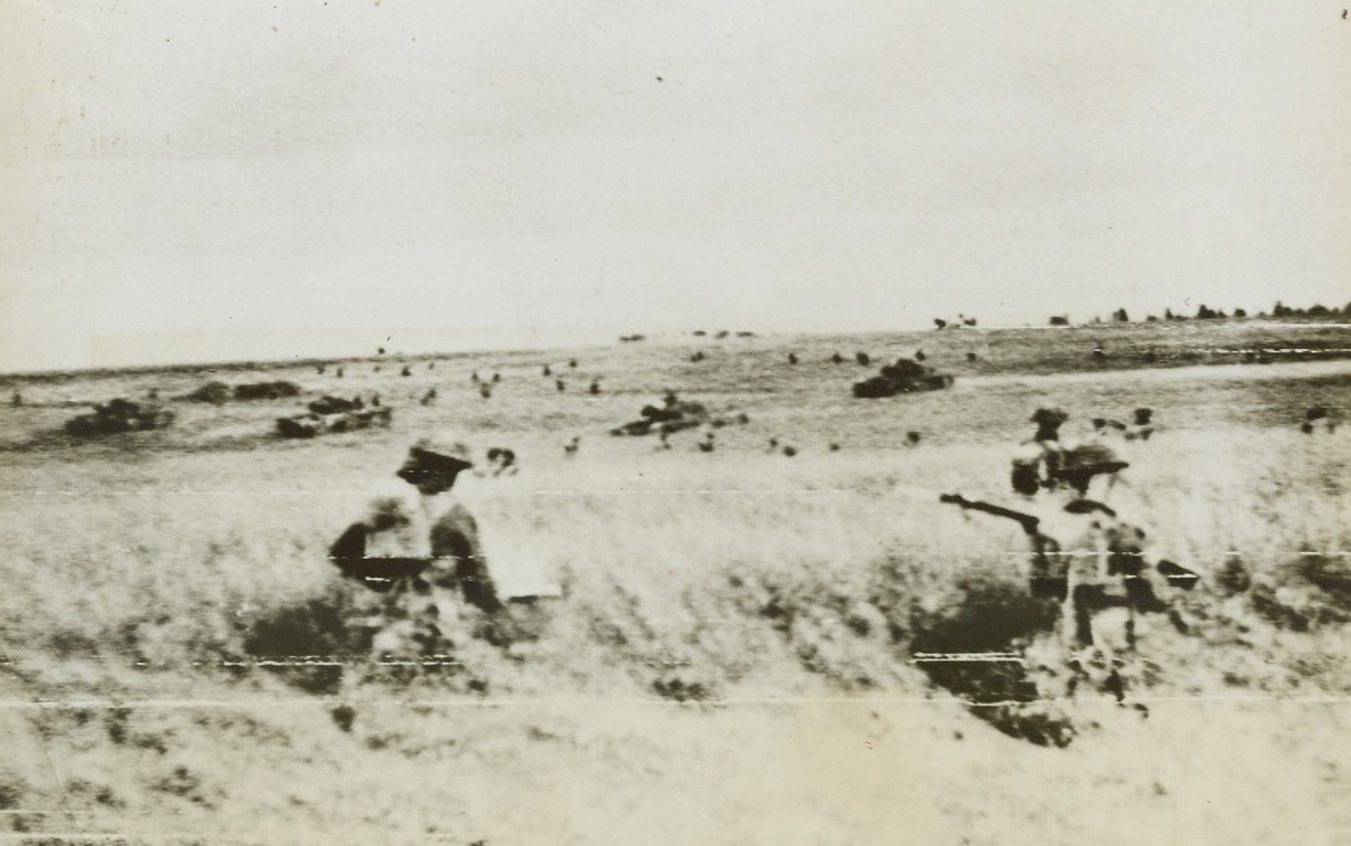 British Advance Near Caen, 6/30/1944. France—British tanks and infantry advance across a cornfield near Caen, France to widen the gap torn in the enemy defenses. A great armored battle is raging south of Caen as British drove on toward the Orne River. Reports from the front state that the enemy is putting up his most desperate defense since American troops cut the Cherbourg Peninsula. Credit: British war office photo via Signal Corps radiotelephoto from ACME;