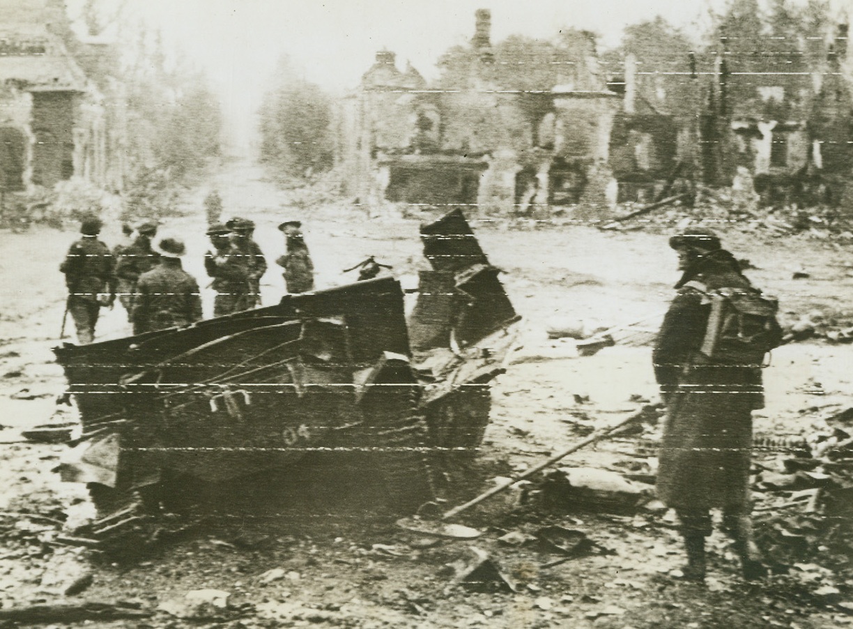 Check for Mines in Rapid Advance, 6/22/1944. France -- A British sapper checks the ground about a smashed bren-gun carrier in the battered streets of Tilly-Burseulles. Other tommies march ahead through the town captured recently after bitter fighting. Credit: British War Office photo from ACME;