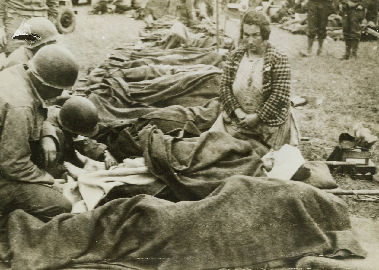 First Aid for French Girl, 6/22/1944. France -- While her mother watches, a young French girl is treated for wounds from German shell fire at an American field hospital in France. A long line of wounded--soldiers and civilians alike--wait their turn for attention from the Yank medics.;