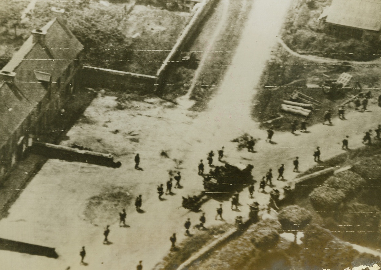 At the Other Side, 6/19/1944. St. Jacques de Nehou, France -- Yanks who have traveled clear across the Cherbourg Peninsula tramp in double column through St. Jacques de Nehou, on the west coast of the Peninsula. Pushing ahead to capture trapped Germans in the area, the Americans now have Jerry with his back against the wall. Latest communiqués from the area indicate that our forces are within seven miles of vital Cherbourg itself. Credit: Signal Corps photo from ACME;