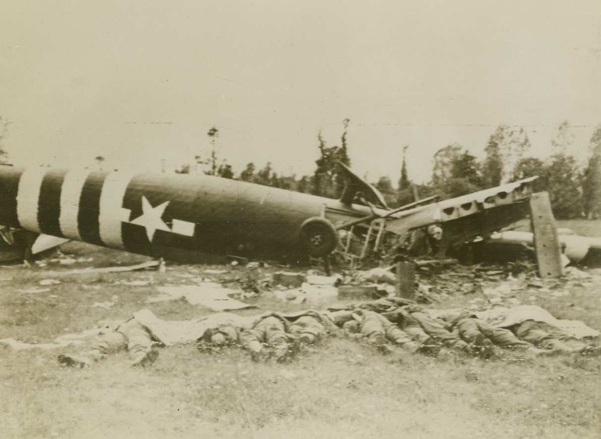 ”We Are the Dead . . . .”, 6/15/1944. Somewhere in France – Parachute shrouds cover the faces of eight airborne infantrymen who lie beside the wreckage of their glider on French soil. The sky fighters were killed during landing operations in France. Credit: British official photo via U.S. Signal Corps Radiotelephoto from Acme;