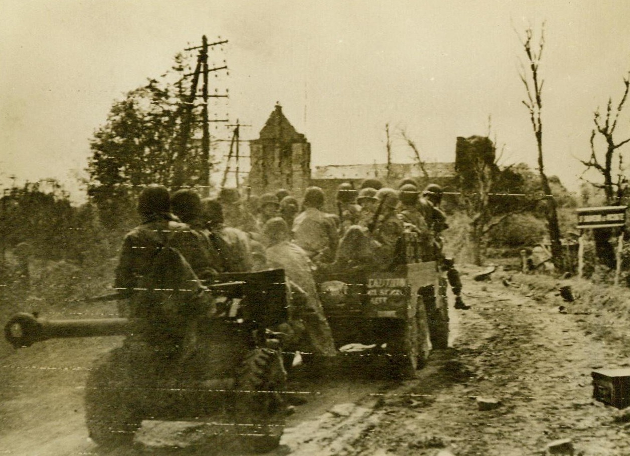 Cherbourg Bound, 6/19/1944. St. Saveur Vicouter, France – Heading for the prize port of Cherbourg, American troops ride through St. Saveur Vicouter, which is in the center of the embattled peninsula. Late reports from the area indicate that the Yanks are within seven miles of Cherbourg. 6/19/44 (Signal Corps Radiotelephoto From ACME);