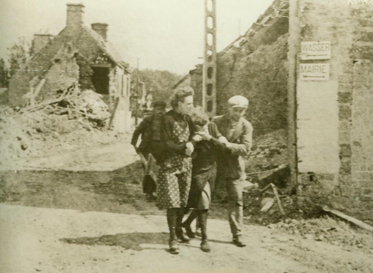 Mourns For Dead Husband, 6/19/1944. France – Weeping hysterically, a village woman of Ste. Marcouf is led away by friends after she discovered that her husband had been killed ruing the German shelling of the little town. She found her husband’s body in a little store to the right, where signs “Wasser” and “Mairie” were nailed up by the Nazis 6/19/44 (Signal Corps Radiotelephoto From ACME);