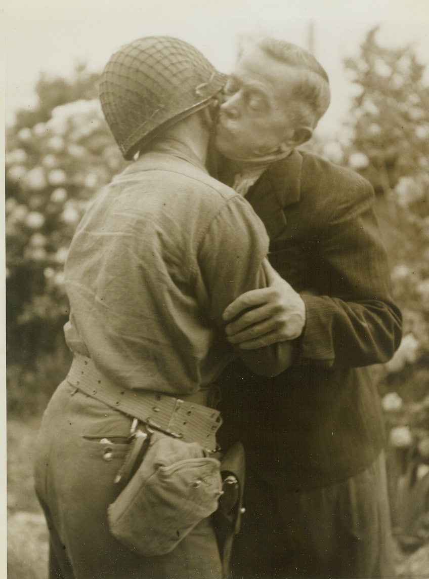 "France Thanks You, My Boy!”, 6/14/1944. Colleville-Sur-Mer, France—With an embrace that seems to express the joyous gratitude of Frenchmen everywhere, the mayor of this tiny hamlet, greets the first American soldier of the forces of liberation entering the village. Credit: ACME photo by Bert Brandt for War Picture Pool;