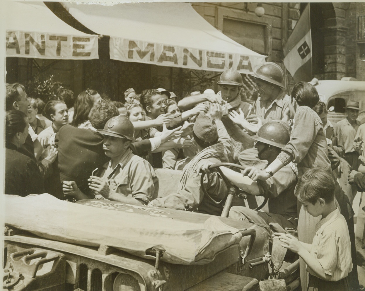 French Liberators in Siena, 7/9/1944. Italy – French troops of the Fifth Army recently captured the historic Italian town of Siena, only 25 miles from Florence. On entering the important town in the north of the Italian peninsula, friendly French soldiers hand out candy and cigarettes to the equally friendly Siena villagers come to greet their liberators. Credit – WP- (AMCE Photo by Charles Seawood, War Pool Correspondent);