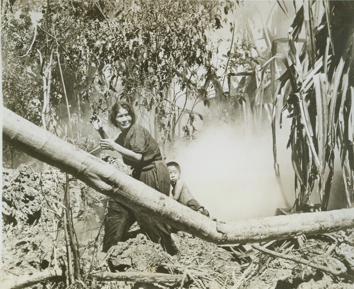 Cave Dwellers Emerge, 7/20/1944. Saipan—After mopping up all resisting Jap troops on Saipan, Yank forces returned inland to a cave containing over one hundred Jap civilians and smoked them out. Among the first of the cave dwellers to emerge from hiding were this woman and child. Both seem frightened and reports from Saipan state that the smoke affected the people so that it was a few minutes before they could speak or see clearly. Credit–WP–(ACME);