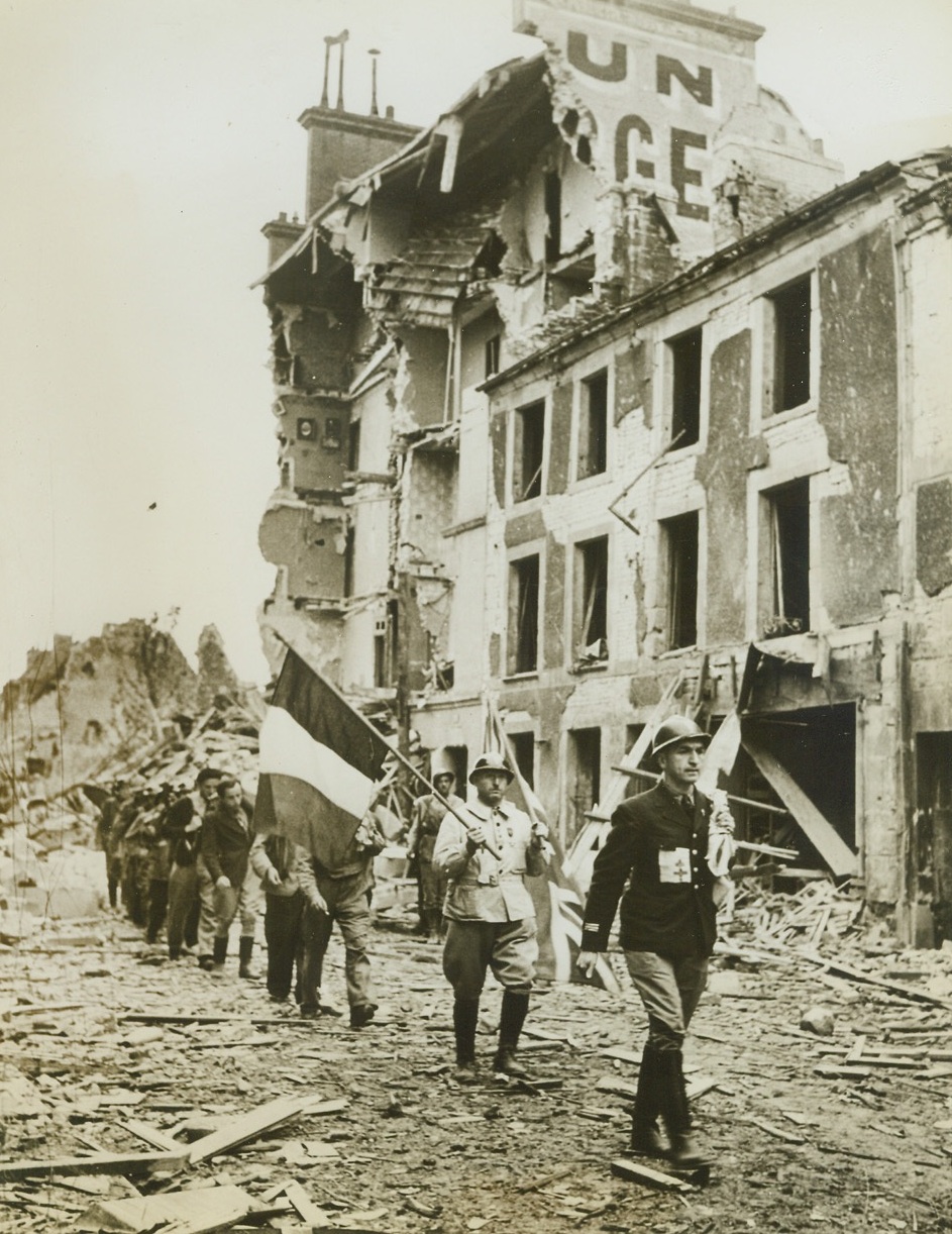 French Underground Emerges, 7/27/1944. Members of the French underground movement advance with medical supplies for villages to the south after the British had stormed the River Orne to take Caen. These patriot Frenchmen carry the tricolor of France and the British Union Jack for identification. Note the first helmeted man in the group wears the Cross of Lorraine sewed to his tunic. Credit-WP-(ACME);