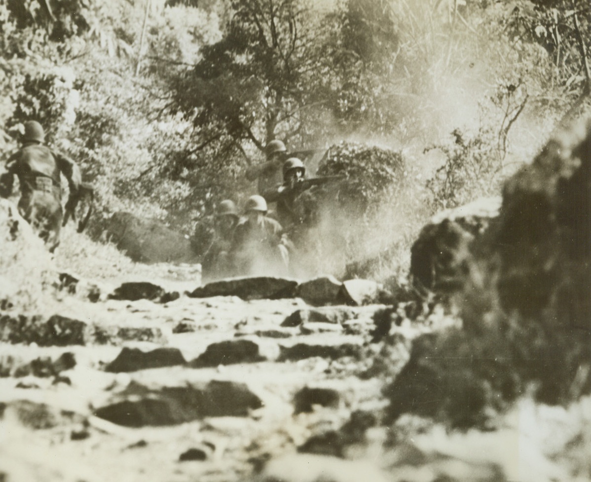 Yanks in a Spot – 3, 7/14/1944. Nemi Valley, Italy – Once the peaceful site of fragrant vineyards and the center of a flourishing wine-grape business, beautiful Nemi Valley, near Rome, was turned into a hot spot recently when a scouting patrol of Yank Infantrymen, guided by Italian partisans, found German strength much greater than they had suspected. Our boys had to fight their way out through holes in a wall of enemy machine gun fire. Here, dashing into cover provided by the bushes at upper left, the Yank shown running in ACME photo # Yan 730150 is safe. His buddies keep their guns barking as they wait for the next member of the patrol to make his break. Credit: Yank Magazine photo from ACME;