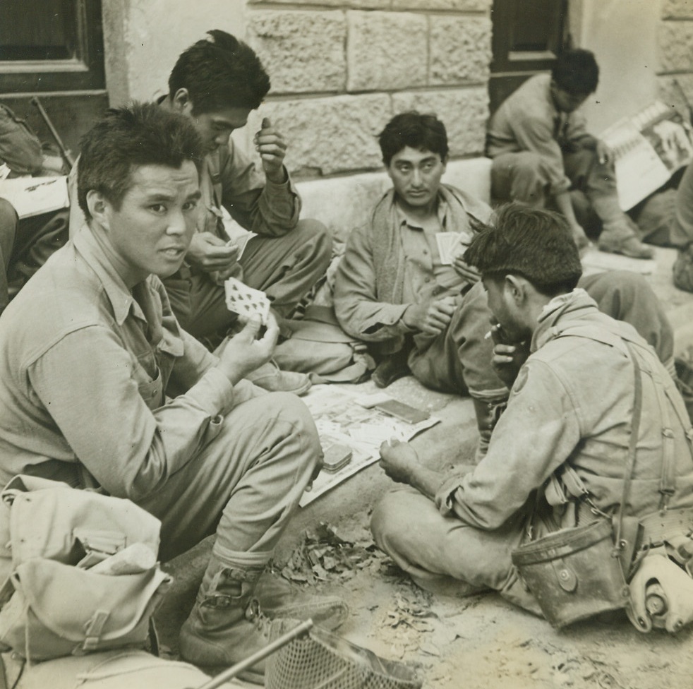 Relaxation’s in the Cards, 7/24/1944. Livorno, Italy – Relaxing in one of the park squares at Livorno, loyal Japanese-Americans squat for a lively poker game.  These are some of the warriors who helped the Fifth Army to take the valuable Italian port.  Credit line –WP- (ACME photo by Sherman Montrose for the War Picture Pool);