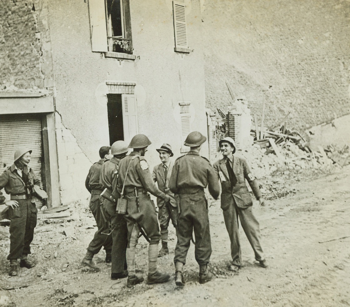 Welcome for Incoming British, 7/14/1944. Caen, France—After a massive land, sea, and air assault, the British and Canadian forces finally entered Caen on July 9, 1944, on the heels of the retreating Germans. Rushing forward to greet the advance troops with smiles of welcome and outstretched hands are Capt. Gille, President of the Committee of Liberation of Calvados, and M. Deuvre, the Prefect of the Calvados, two patriots who remained in the ruined town. Credit: British official photo from ACME;