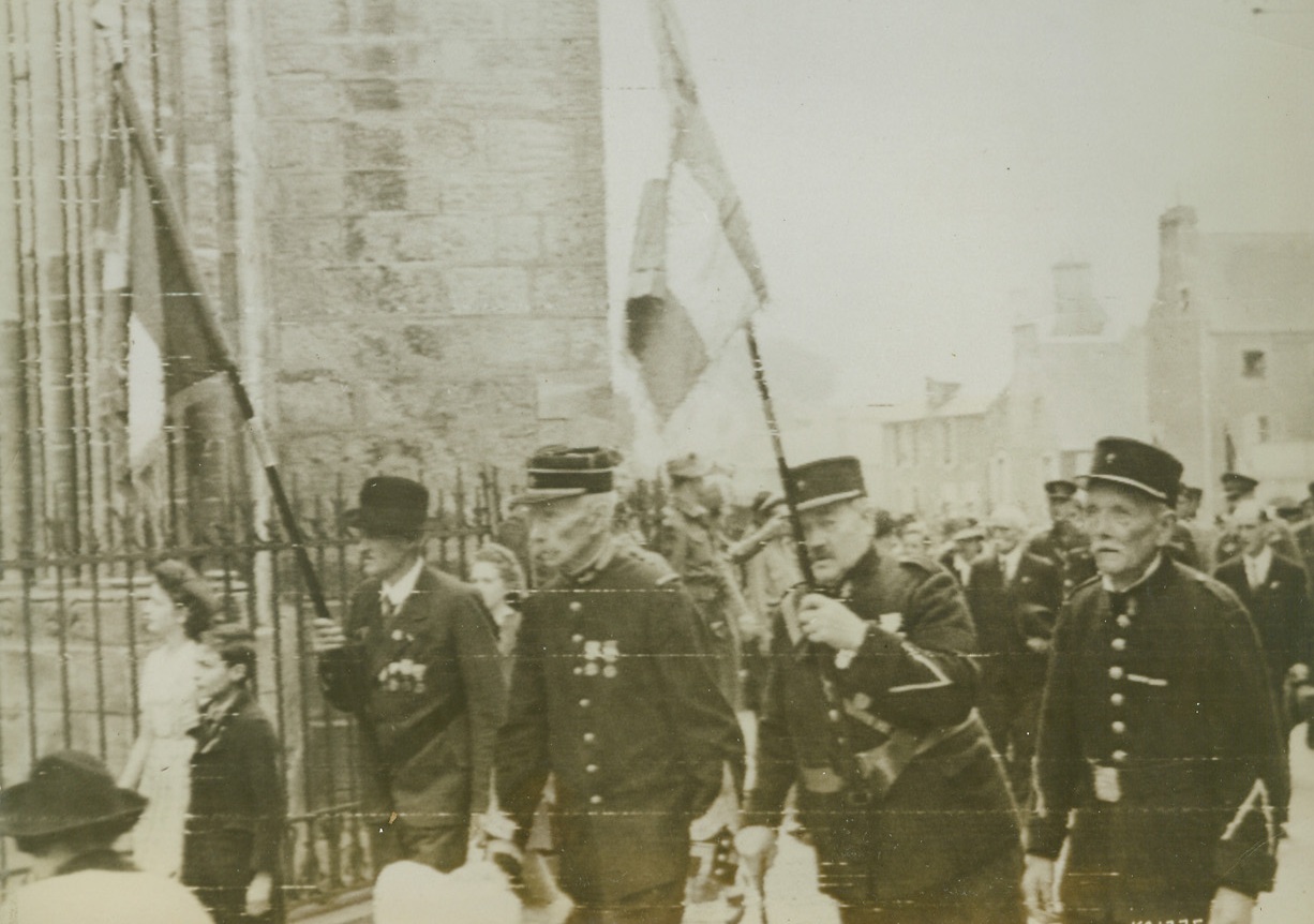 FRENCH ARMY VETS FETE BASTILLE DAY, 7/15/1944. FRANCE—Proudly carrying the tricolor of France, these French Army veterans march through a street in Bayeux, France, during Bastille Day celebrations. British troops in the French town joined in the festivities which symbolize the triumph of freedom for the peoples of the world. Credit (Signal Corps Radiotelephoto from ACME);