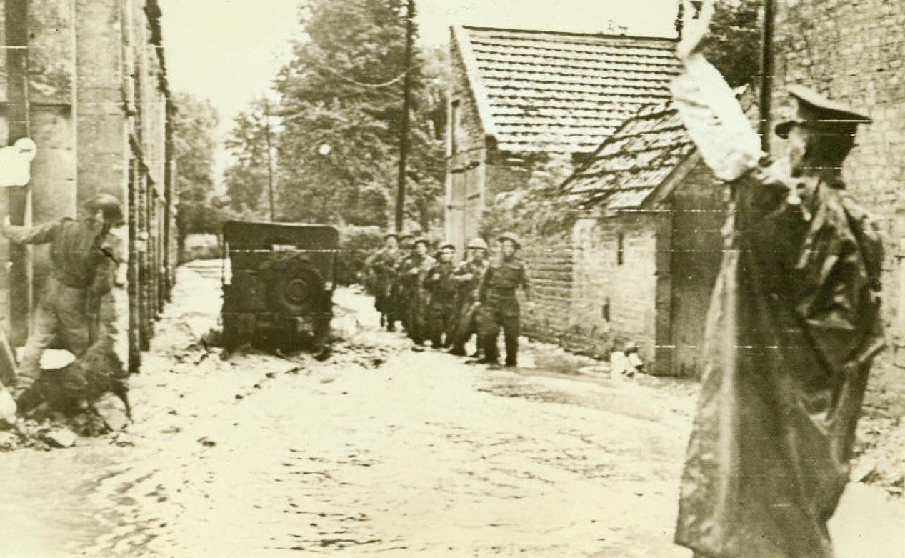 And The Rains Came, 7/24/1944. Normandy, France - Battling the Germans in the area around Caen, British troops had to combat heavy rains as well as enemy fire. Here British Tommies advance through a small village, marching knee-deep in water while their vehicles bog down in the mud. Credit: US Army Radiotelephoto from ACME;