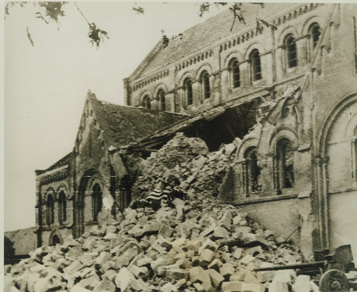 Old Glory Marks Victory At St. Lo, 7/20/1944. France—An American flag (center) has been placed amid the ruins of Holy Cross Church in this important Normandy city, marking the defeat of Germans by U.S. forces. Note half-buried field gun (lower right). Credit: ACME photo via Army radiotelephoto;