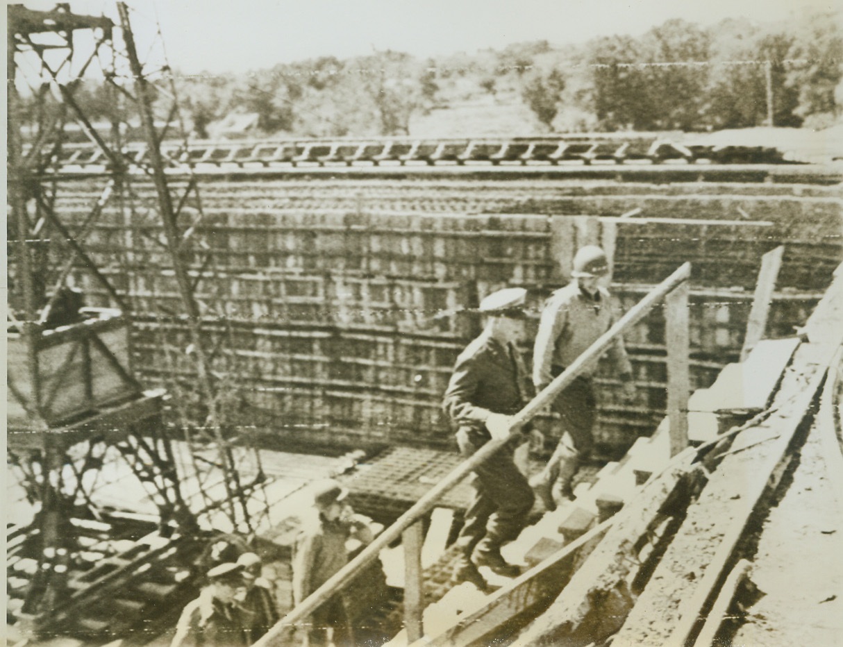 Four Star Independence Day Visitor, 7/6/1944. Normandy—Accompanied by Lt. General Omar N. Bradley, General Dwight D. Eisenhower (second from top of steps) climbs from the base of a rocket bomb launching platform captured by the Yanks somewhere in Normandy. “Ike” visited the launching site as part of his Independence Day tour of the Normandy front. Credit: Signal Corps radiotelephoto from ACME;