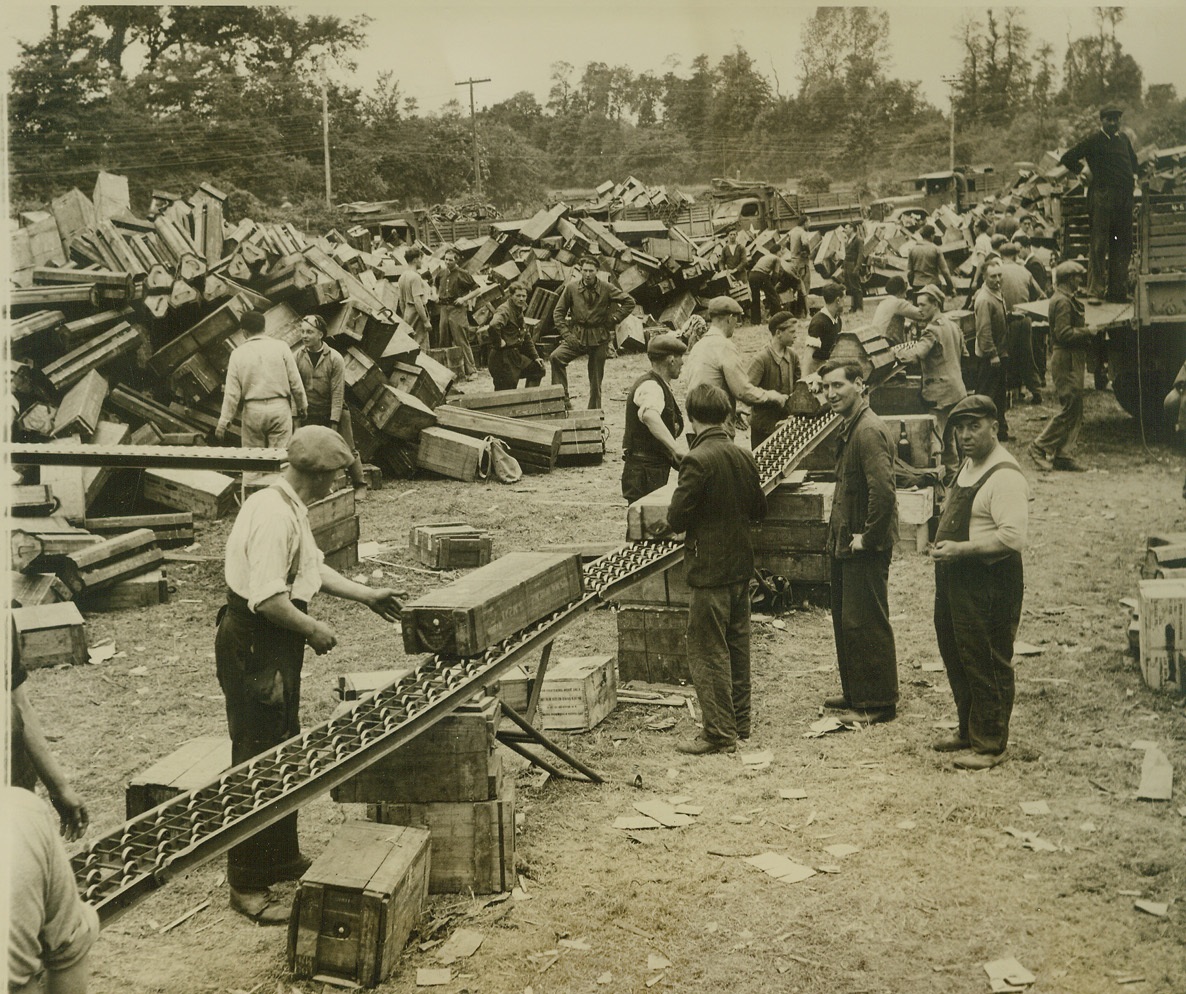 Frenchmen Aid Allied Armies, 7/6/1944. France—French civilians are now finding work with the Allied forces in Normandy. Here a group of workers help sort ammunition at one of the huge dumps built at a bridgehead. A roller stack speeds up the heavy work. Credit: ACME photo by Bert Brandt, War Pool Correspondent;