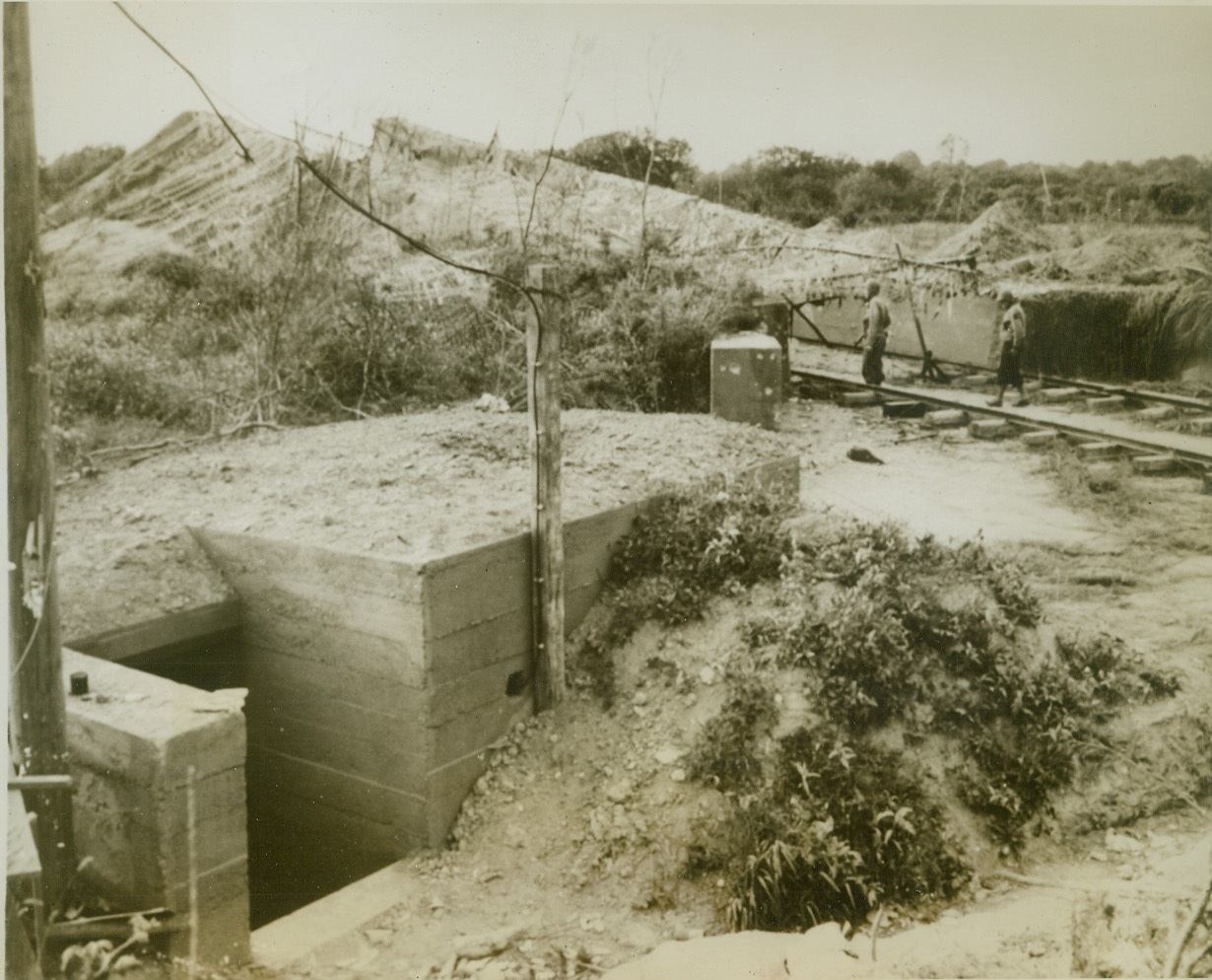 Yanks Take Launching Site, 7/2/1944. Delassy, France—A pair of American soldiers examine one of the robot bomb launching sites captured by our forces in France. This launching platform, not far from the town of Delassy, is reinforced with concrete and camouflaged.  Credit: ACME;