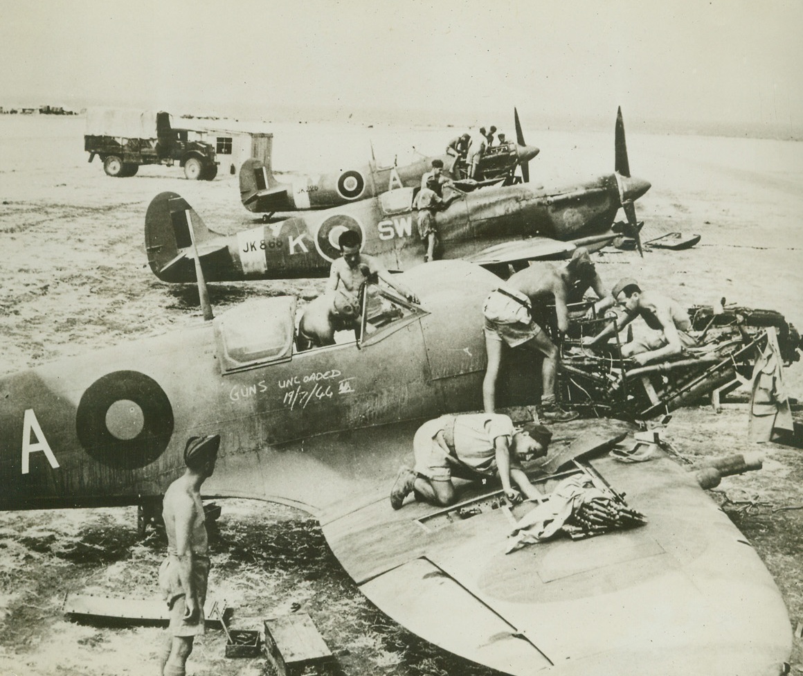 Partisans Learn Plane Mechanics, 8/18/1944. ITALY – In Liberated Italy a specially selected group of Marshal Tito’s Yogoslav Partisan Army is being trained along with RAF ground crews in the intricacies of modern airplane mechanics. All the men have been chosen for particular abilities. Their teachers are RAF non-coms. Photo shows Partisans and men of the Royal Air Force hard at work on a trio of Spitfires.Credit (British Official Photo from Acme);