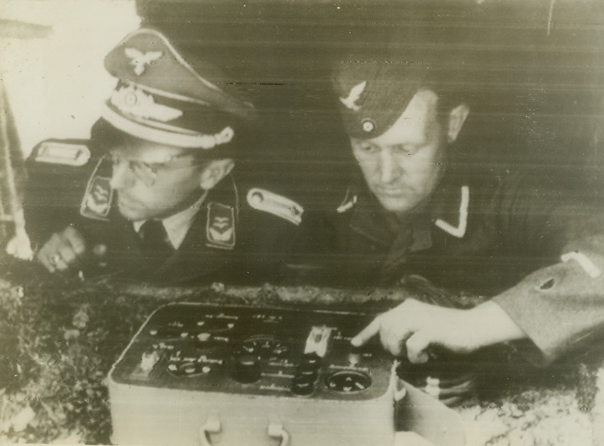 THE MEN BEHIND THE BOMBS, 8/17/1944. FRANCE – In this photo, radioed from Stockholm today (August 17), two Nazi soldiers, one with his finger on the button, are operating the switchboard which releases the flying bombs somewhere in France.  According to the German caption, the bombs are being directed against London.Credit: Acme;