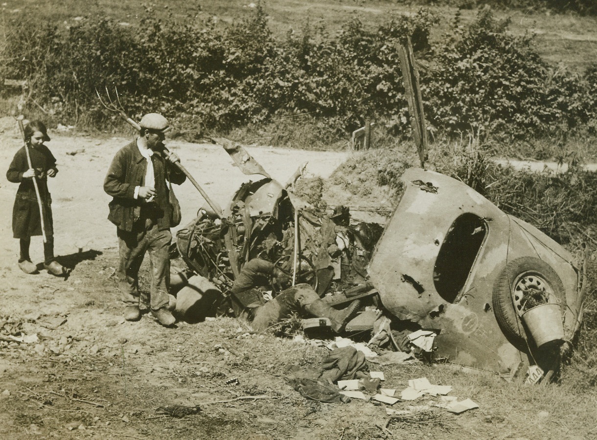 GRIM REMINDER OF WAR, 8/22/1944. MORTAIN, FRANCE – On their way to the fields this French peasant and his little girl pass a Nazi staff car and its dead driver, caught by shell fire at a crossroads near Mortain.  Accustomed to such sights, the two give it only a passing glance.Credit: Signal Corps photo from Acme;