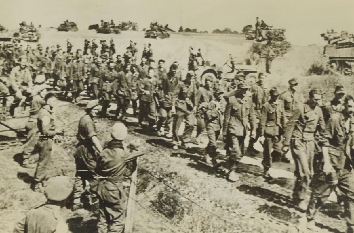 Two-Way Traffic, 8/23/1944. France – Past a long column of dejected German prisoners being marched to the rear, British armored vehicles rumble ahead toward the front. Nazis were taken when the Falaise-Argentan Gap was closed by Allied Forces cutting off any possible escape route for an estimated 100,000 Germans. Credit: British War Office photo via Army Radiotelephoto from ACME;